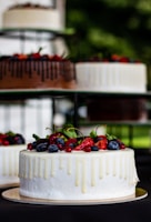 An elegant cake decorated with fresh berries and a glossy glaze on a minimalist stand.
