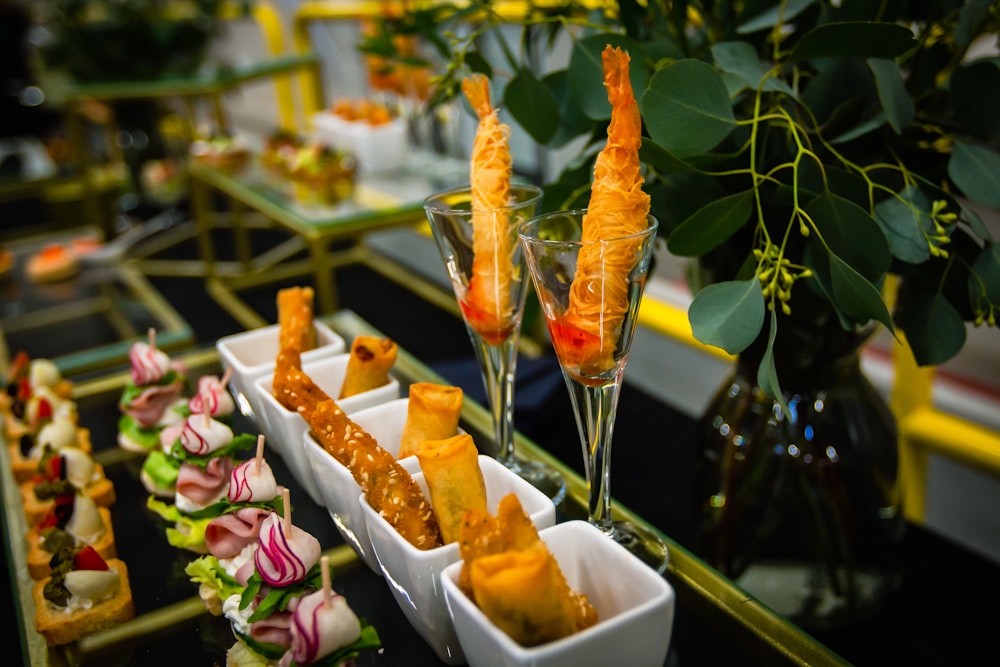 a table topped with trays of food next to a vase filled with flowers