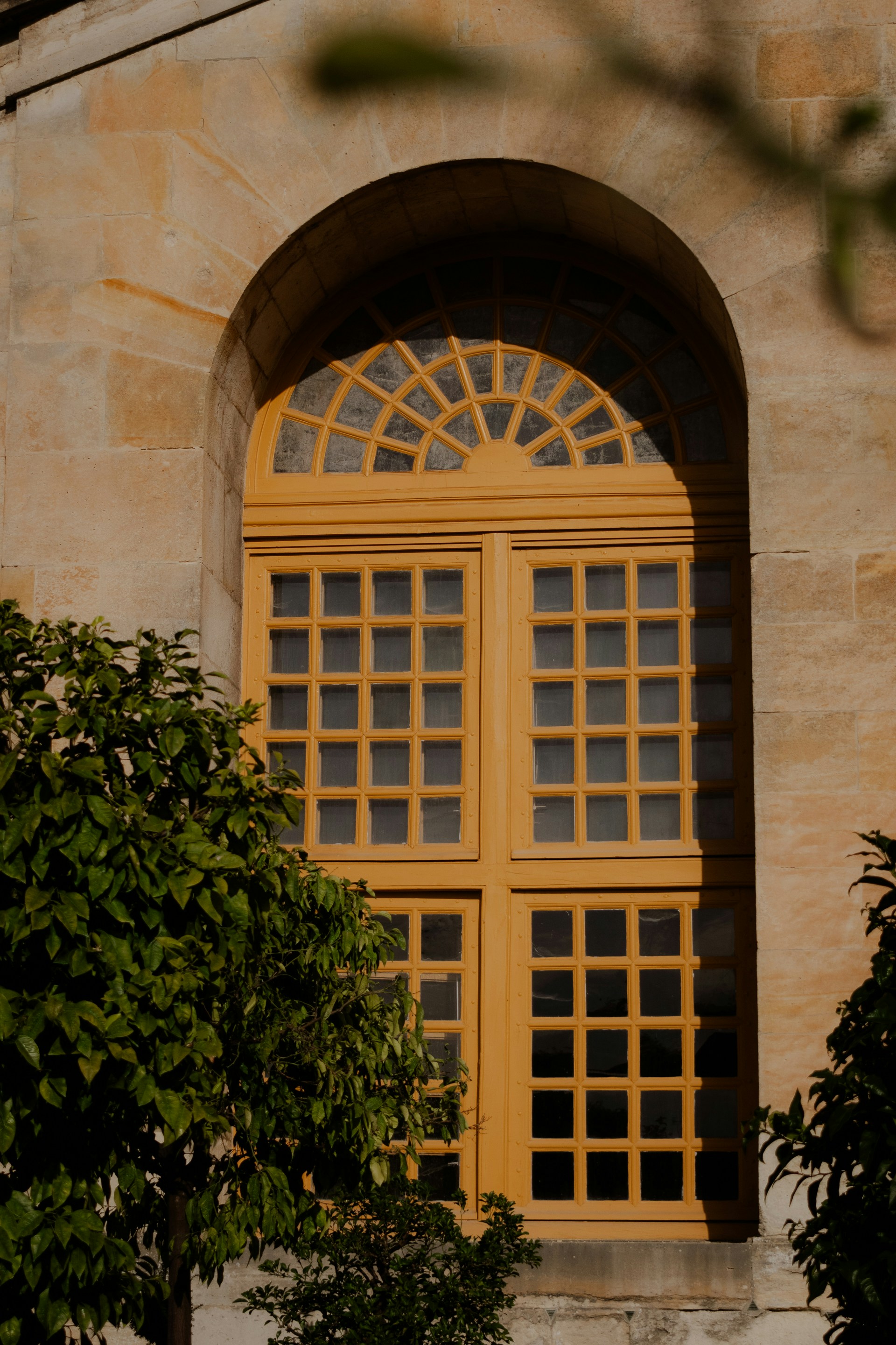 a yellow window with arched glass on a stone building