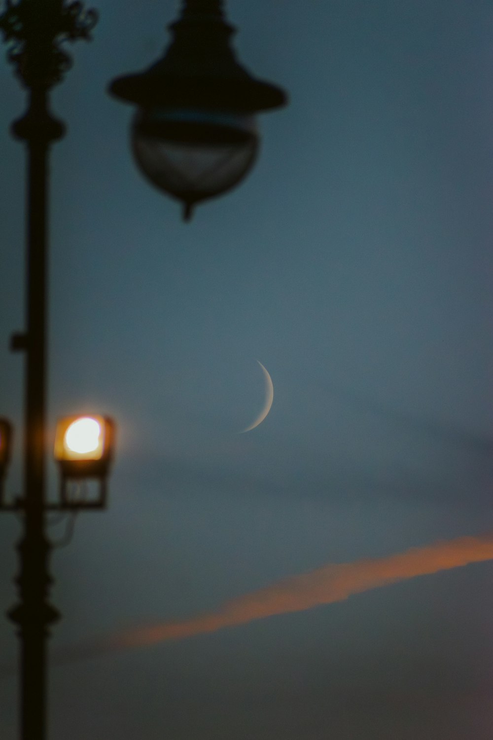a street light with the moon in the background