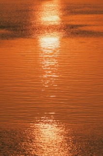 the sun is setting over the water of a lake