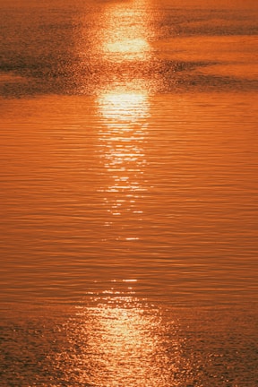 the sun is setting over the water of a lake