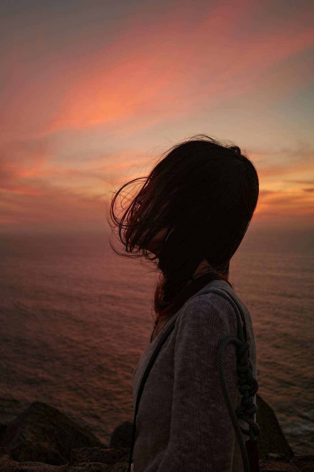 a woman looking out at the ocean at sunset