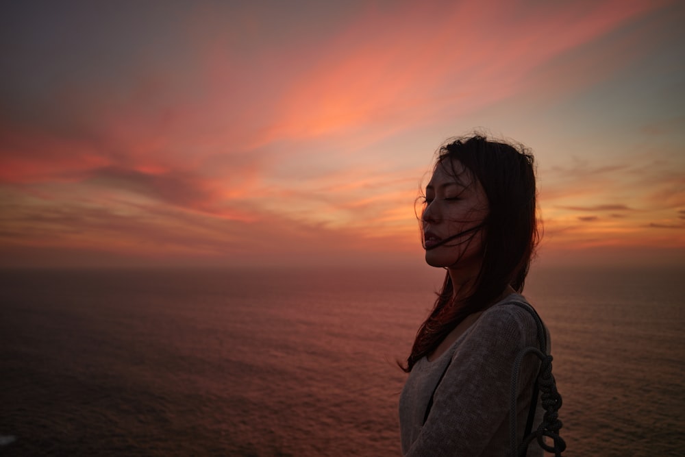 a woman with painted face standing in front of a sunset