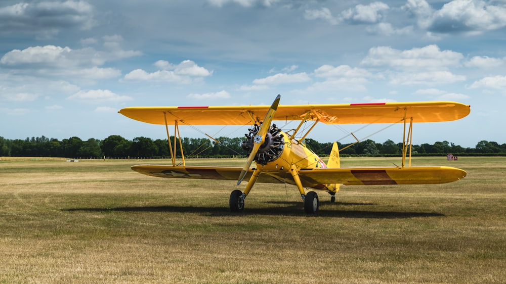 a yellow airplane sitting on top of a grass covered field