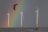 Three large wind turbines stand in a body of water with a vibrant rainbow in the background. A person is kite surfing near the turbines, with a red kite visible above.