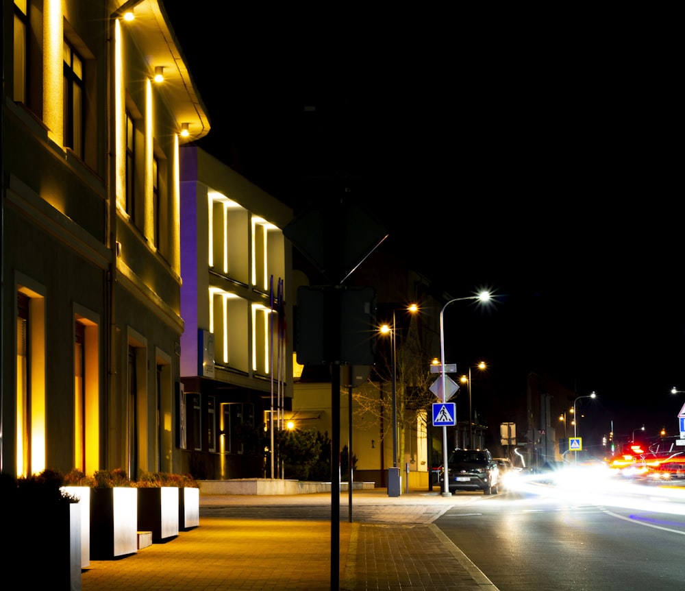 a city street at night with cars passing by