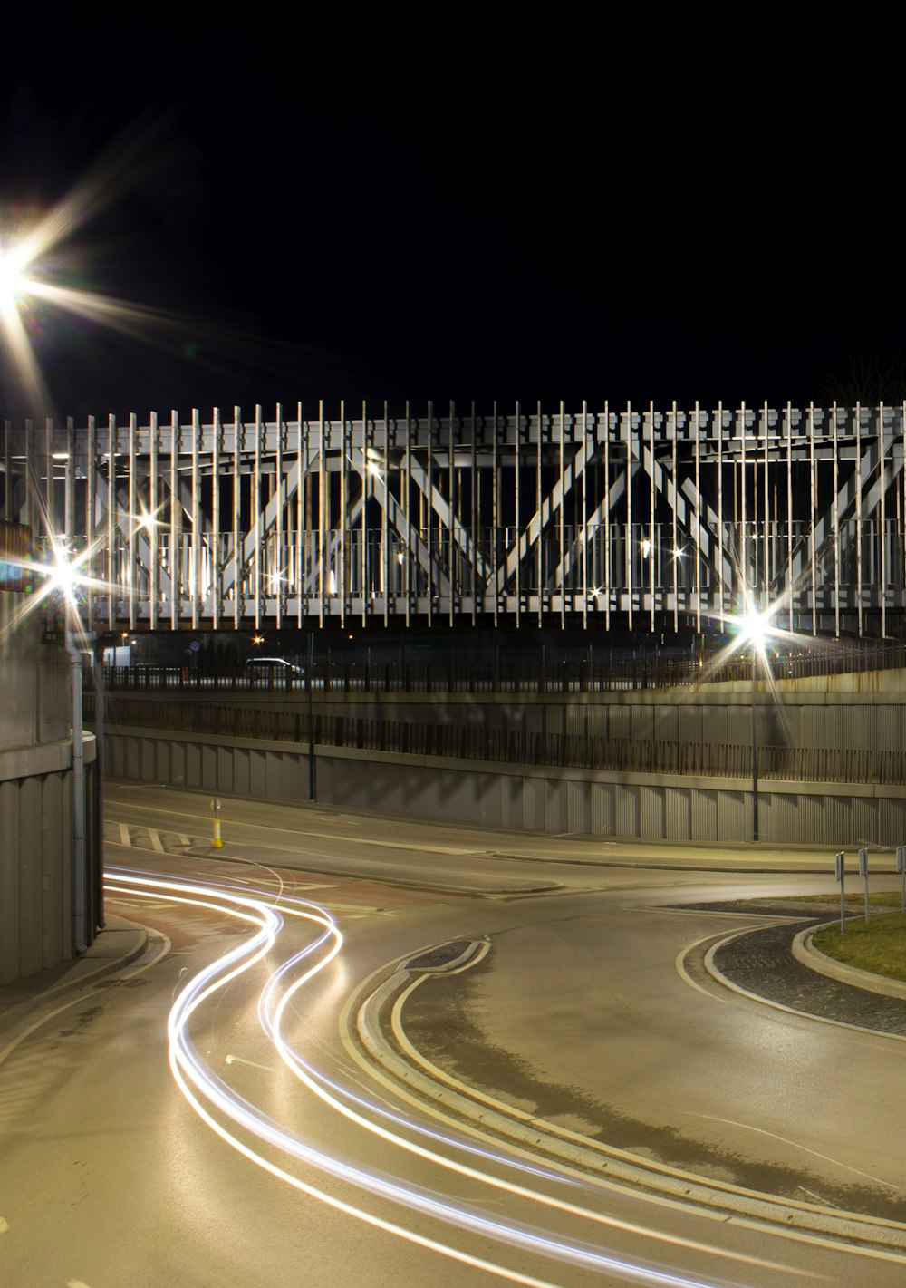 a night time picture of a street with a bridge in the background