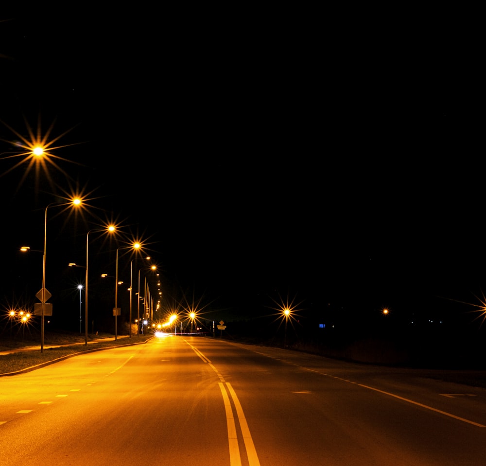 eine Straße bei Nacht mit Straßenlaternen und Straßenschildern
