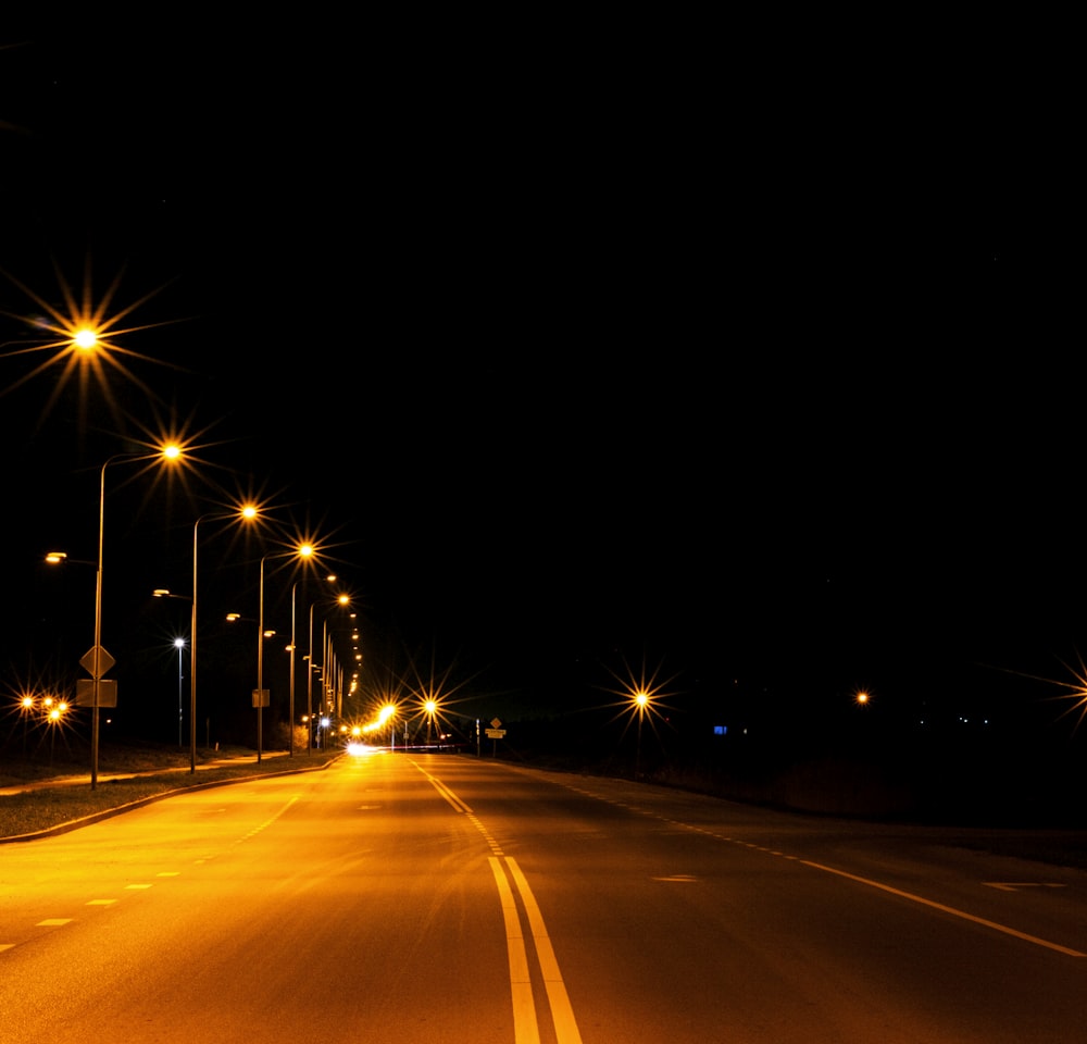 uma rua à noite com iluminação pública e sinais de rua