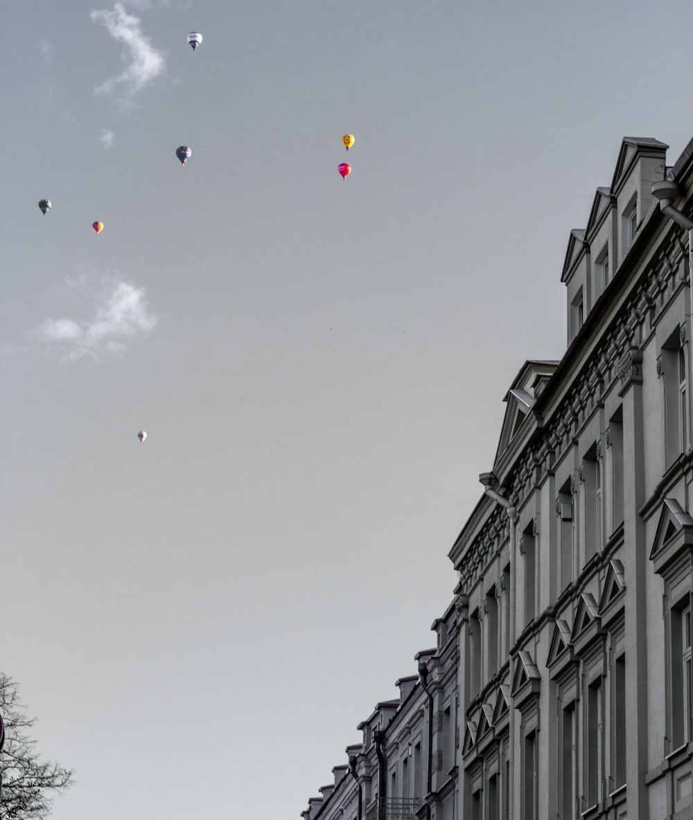 eine Gruppe von Drachen, die am Himmel über einem Gebäude fliegen