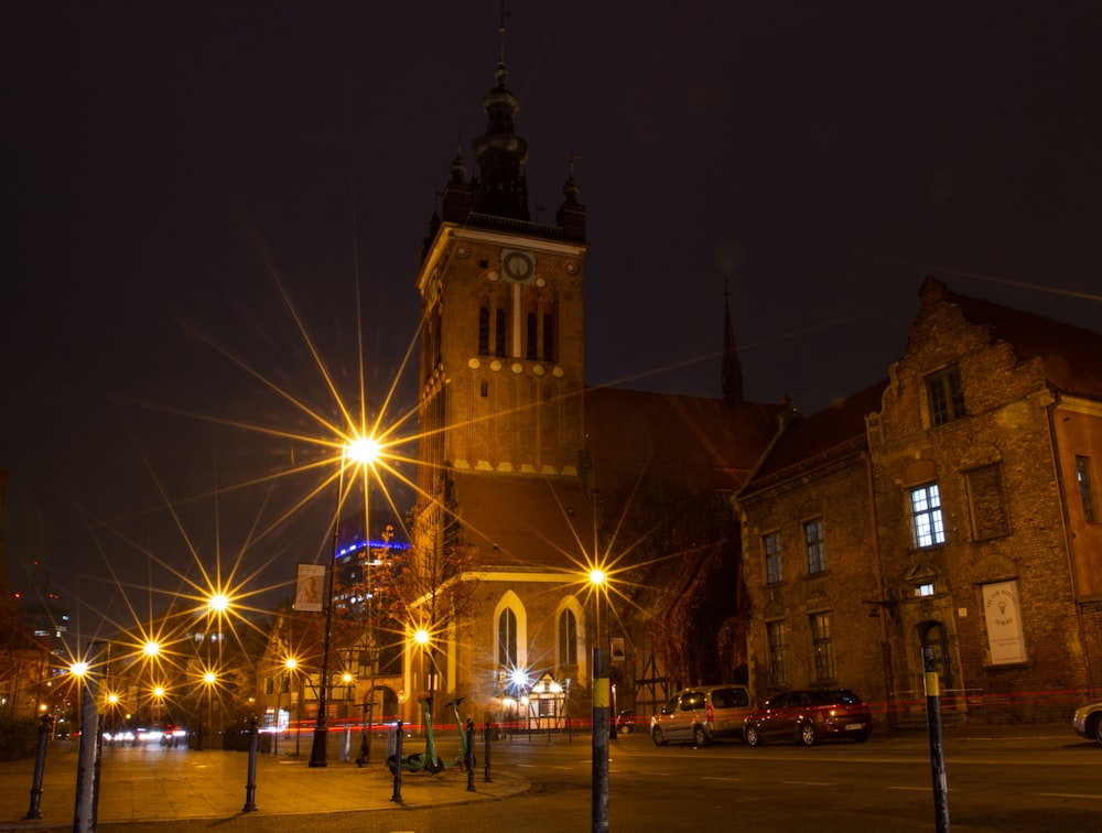 Una strada della città di notte con una torre dell'orologio sullo sfondo