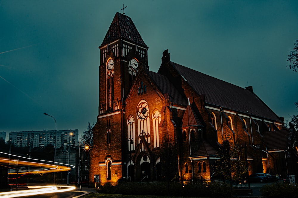 uma igreja com uma torre de relógio iluminada à noite