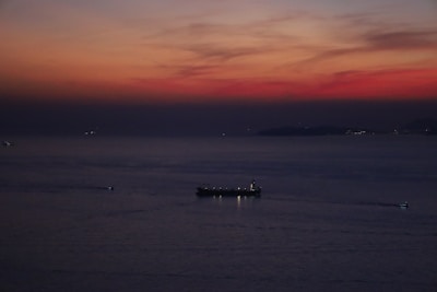 A large oil tanker ship loading crude oil at sunset on the open sea.