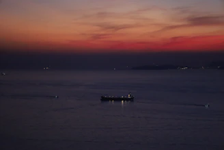 A commanding shot of a large cargo ship at dusk, loaded with energy commodities, navigating open waters.