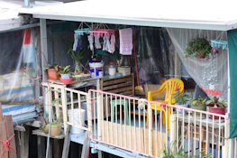 Bright balcony decorated with bohemian cushions and potted plants.