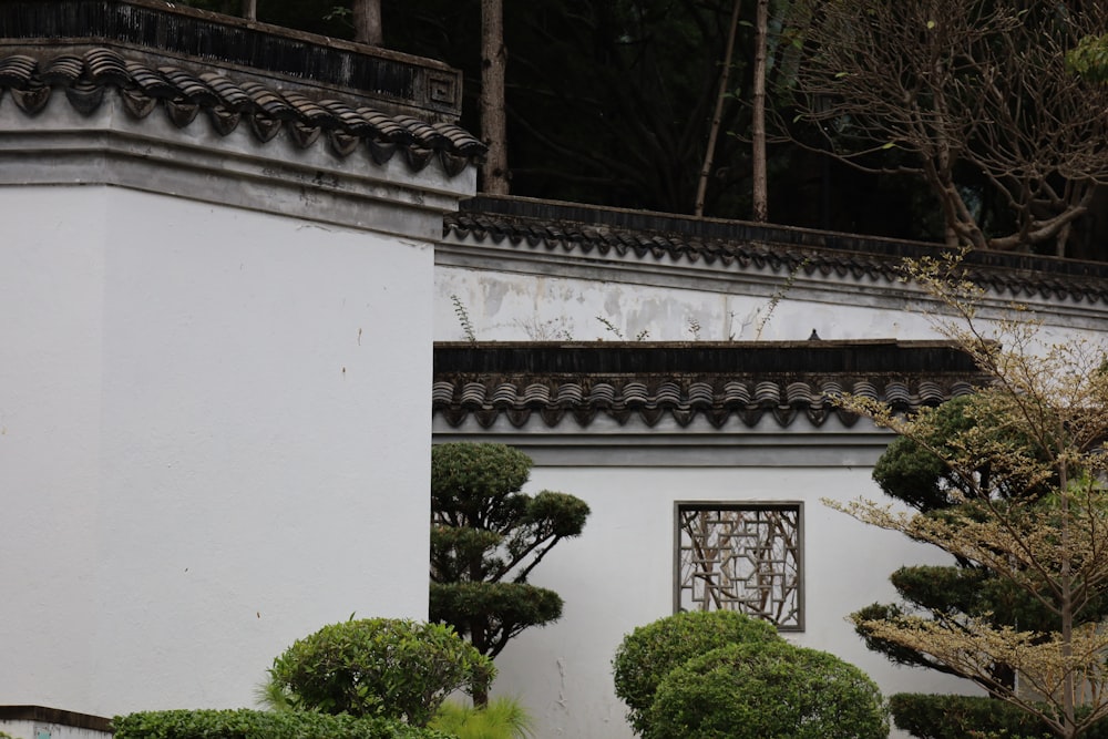 a white building with trees and bushes in front of it