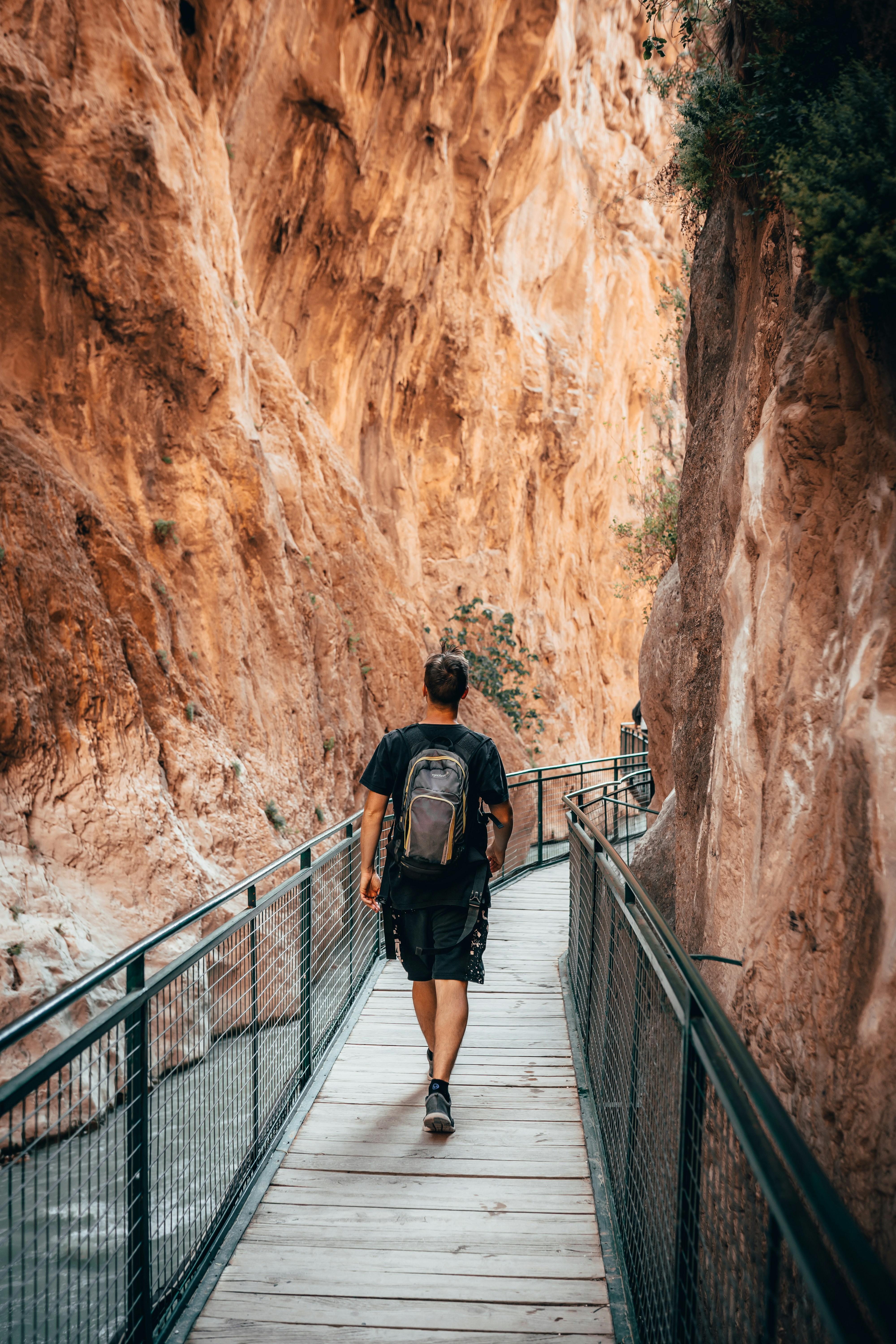 a man with a backpack walking down a wooden walkway