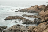 The rugged coastline of the Great Ocean Road with crashing waves under a cloudy sky.