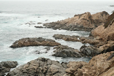 The rugged coastline of the Great Ocean Road with crashing waves under a cloudy sky.