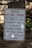 A warning sign is placed outdoors against a background of stone steps and walls, surrounded by some greenery. The sign indicates that the building is vacant and unauthorized entry is prohibited. Contact information for further inquiries is provided at the bottom.
