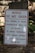 A warning sign is placed outdoors against a background of stone steps and walls, surrounded by some greenery. The sign indicates that the building is vacant and unauthorized entry is prohibited. Contact information for further inquiries is provided at the bottom.