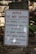 A warning sign is placed outdoors against a background of stone steps and walls, surrounded by some greenery. The sign indicates that the building is vacant and unauthorized entry is prohibited. Contact information for further inquiries is provided at the bottom.