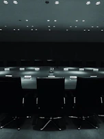 Close-up of a business conference room bathed in moody blue lighting, highlighting focused faces and sharp details.