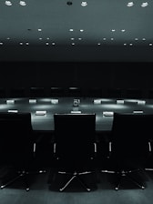 A formal meeting room with professionals discussing technical documents, reflecting a serious and institutional atmosphere.