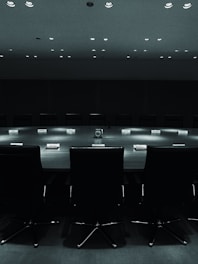 A sleek, dark-themed meeting room with a large table and comfortable chairs, softly lit.