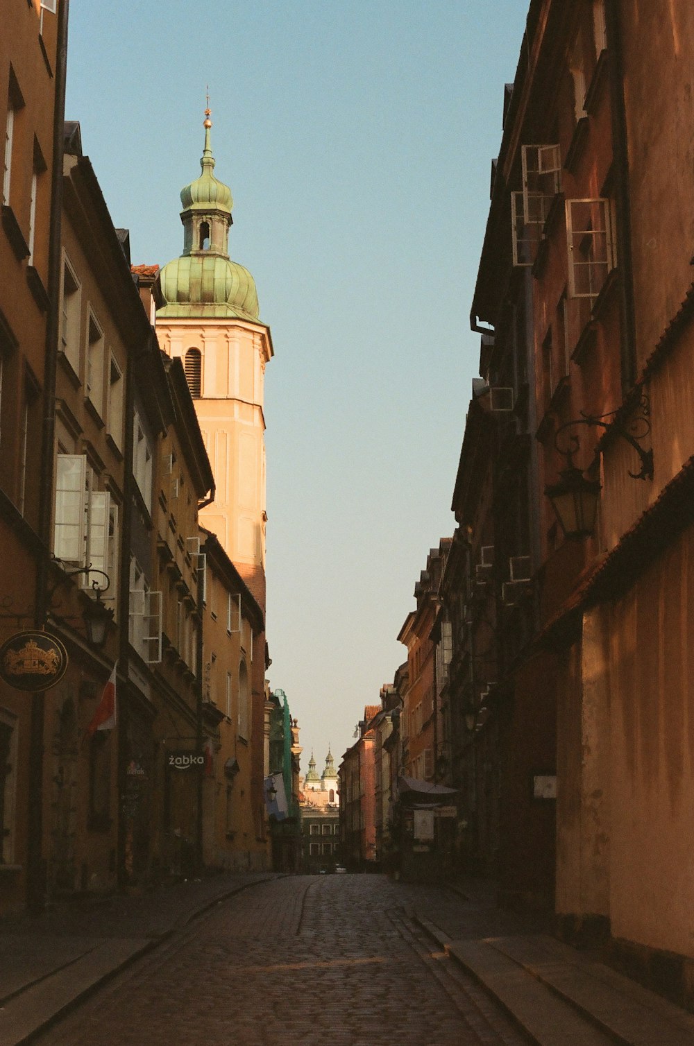 a narrow city street with a clock tower in the background