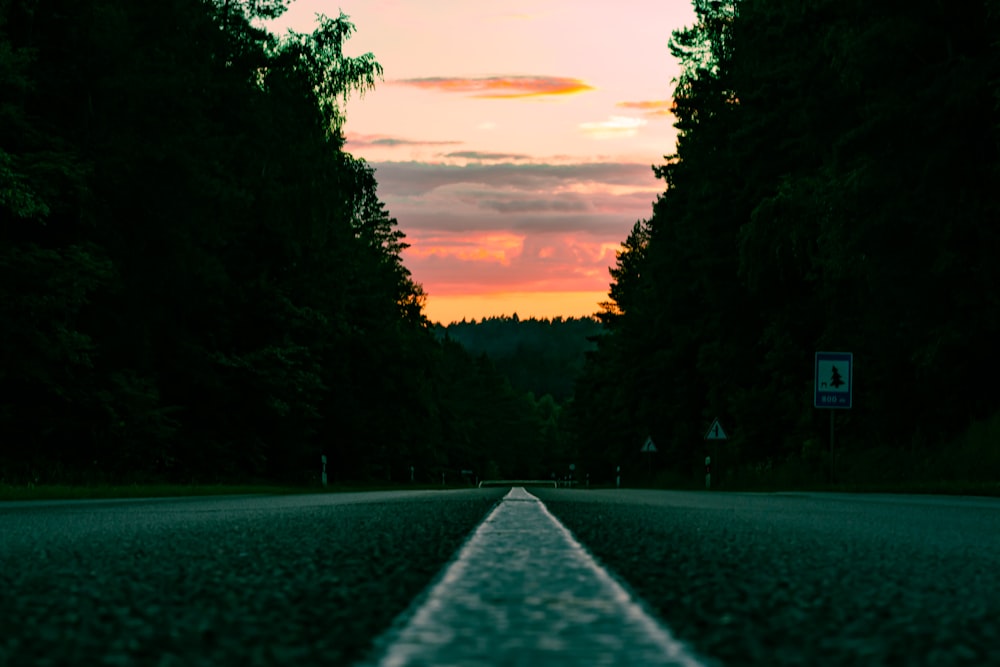 a long straight road with a sunset in the background