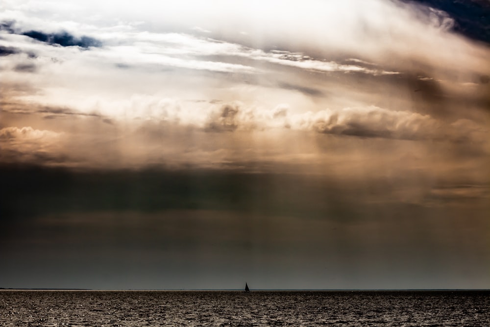 a boat in the ocean under a cloudy sky