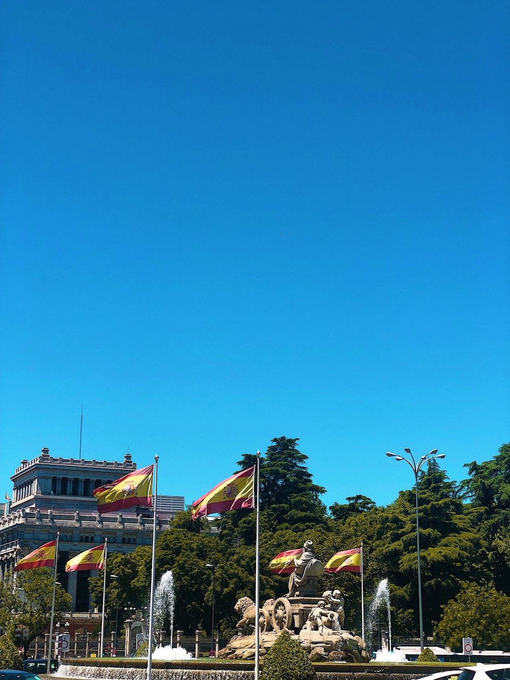 a fountain in a park with flags flying in the wind