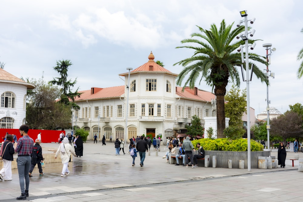 a group of people walking in front of a large white building