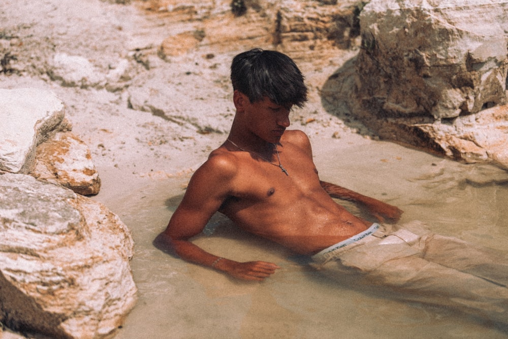 a shirtless man laying in a pool of water