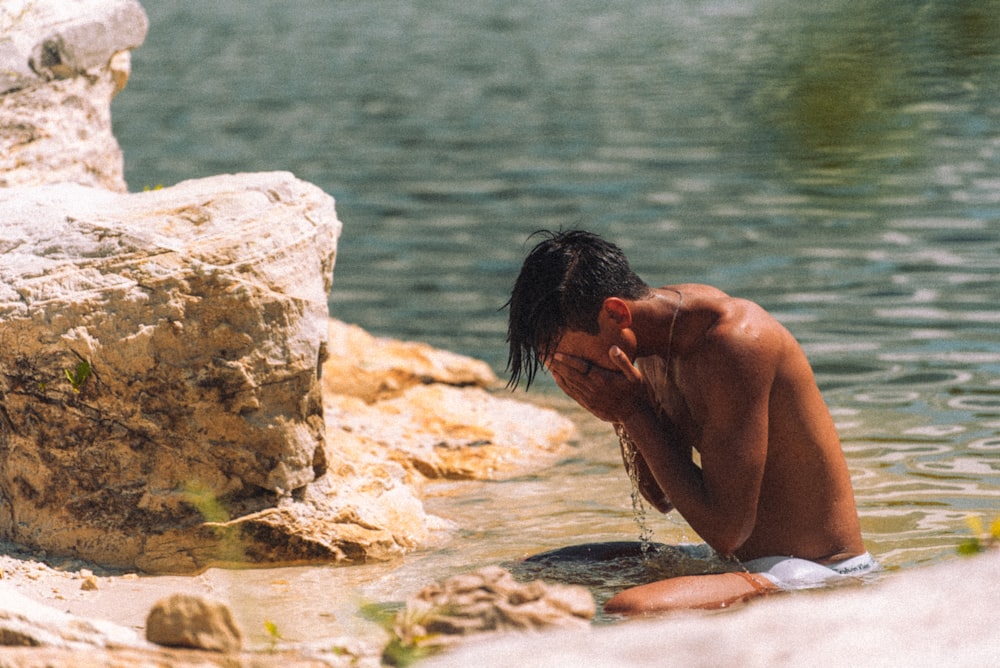 a man sitting in the water with his head in his hands