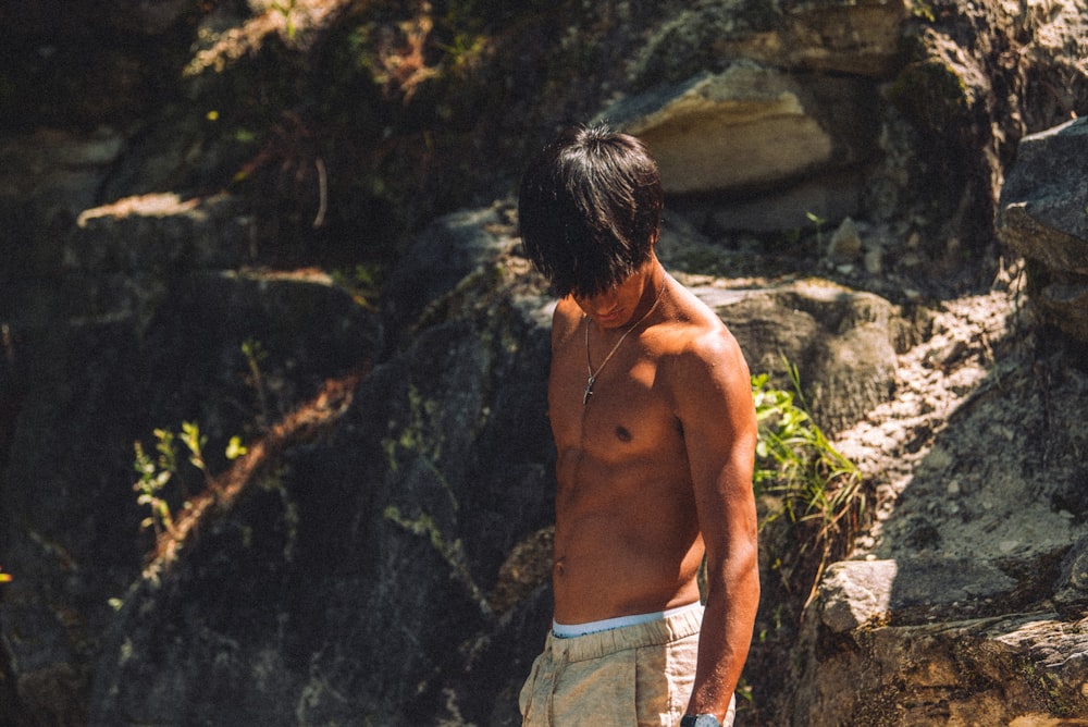 a shirtless man standing in front of a rocky cliff