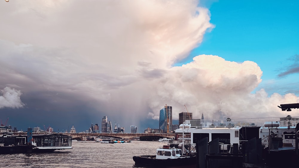 a group of boats floating on top of a river under a cloudy sky