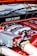 A close-up view of a car engine featuring prominently the words 'Made in Japan' and 'Twin Turbo'. The engine components are detailed, with visible pipes, bolts, and metal surfaces. The colors red and silver are dominant in the design, indicating performance and craftsmanship.