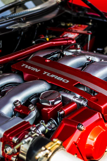 Close-up shot of a twin-turbo engine with glowing manifolds and carbon fiber textures under moody industrial lighting.