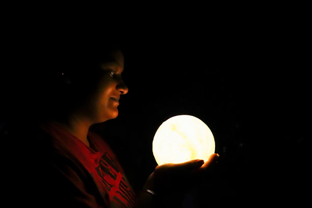 A close-up of a person holding a glowing crystal ball under soft, warm lighting.