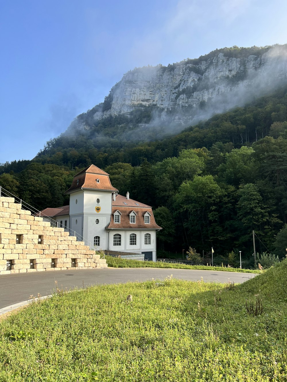 a white house with a red roof and a mountain in the background