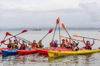 A group of people paddling kayaks on calm blue waters under a sunny sky.