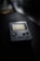 A vintage handheld gaming console with a screen and control buttons is placed on a dark surface. The focus is on the console, with the background blurred, creating a nostalgic atmosphere.