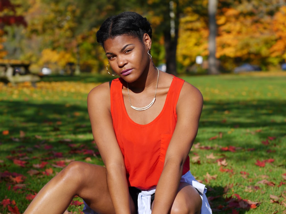 a woman sitting on the ground in a park