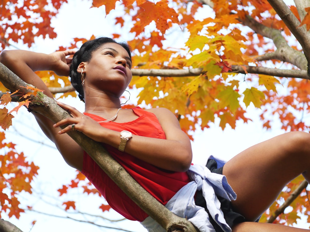 a woman sitting on a tree branch in the fall