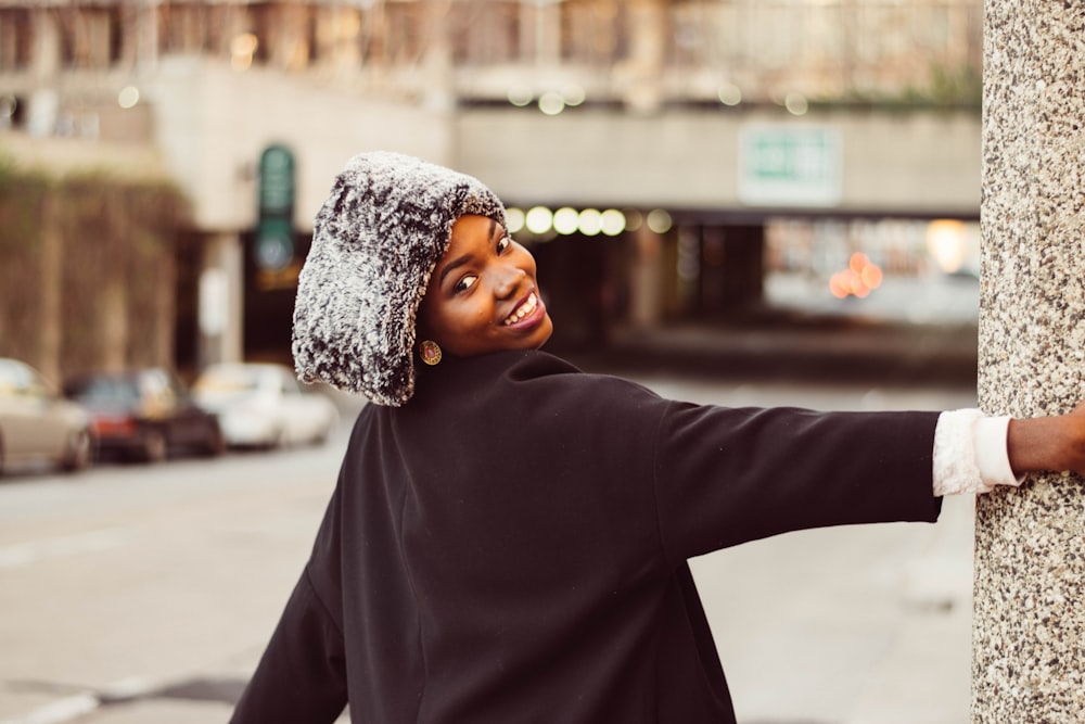 a woman leaning against a pole on a city street