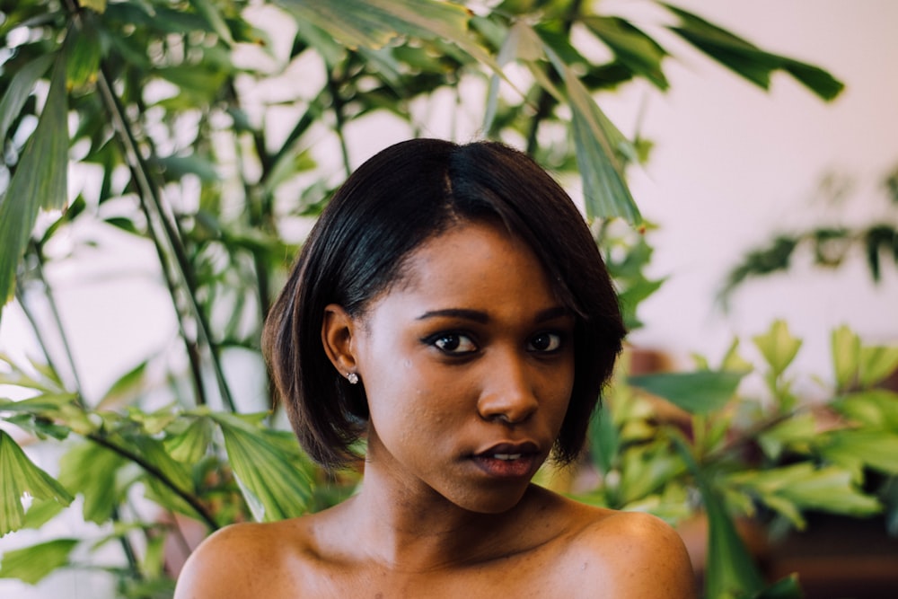 a young woman is posing in front of a potted plant