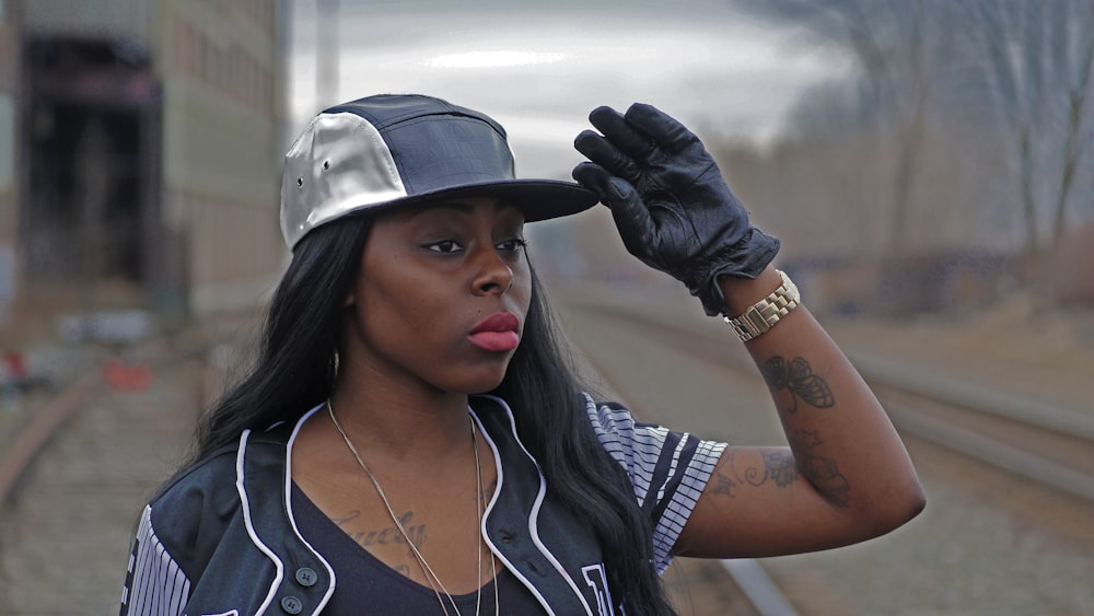 a woman wearing a hat and gloves on a train track